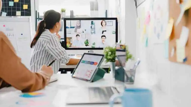 Teammeeting mit hybrider Arbeitsweise – Mitarbeitende im Büro und per Videokonferenz zugeschaltet